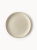 A top-down view of a round stoneware plate featuring a speckled cream finish and a natural brown rim.