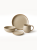 A minimalist stoneware dinnerware set in a speckled beige finish with a natural brown rim is arranged against a plain white background. The collection features a large dinner plate, a medium bowl, a small saucer, and a matching mug.