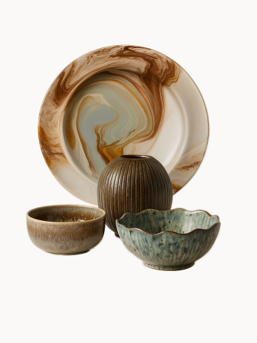 A decorative set of rustic table accessories features a large brown and grey marbled plate, a ribbed dark brown ceramic vase, and two speckled bowls, one with a wavy edge. The entire collection is isolated against a solid white background.