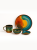 A vibrant ceramic tableware set with a glossy, colorful reactive glaze is arranged against a solid white background. The collection includes a large artistic plate with orange and teal patterns, a matching mug, a medium bowl, and a small saucer.