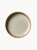 A top-down view of a round ceramic plate featuring a speckled, light grey glazed interior and a thick, unglazed natural terracotta rim.
