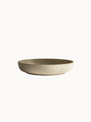 A shallow, round ceramic bowl with a speckled beige and light grey texture, on a plain white background.