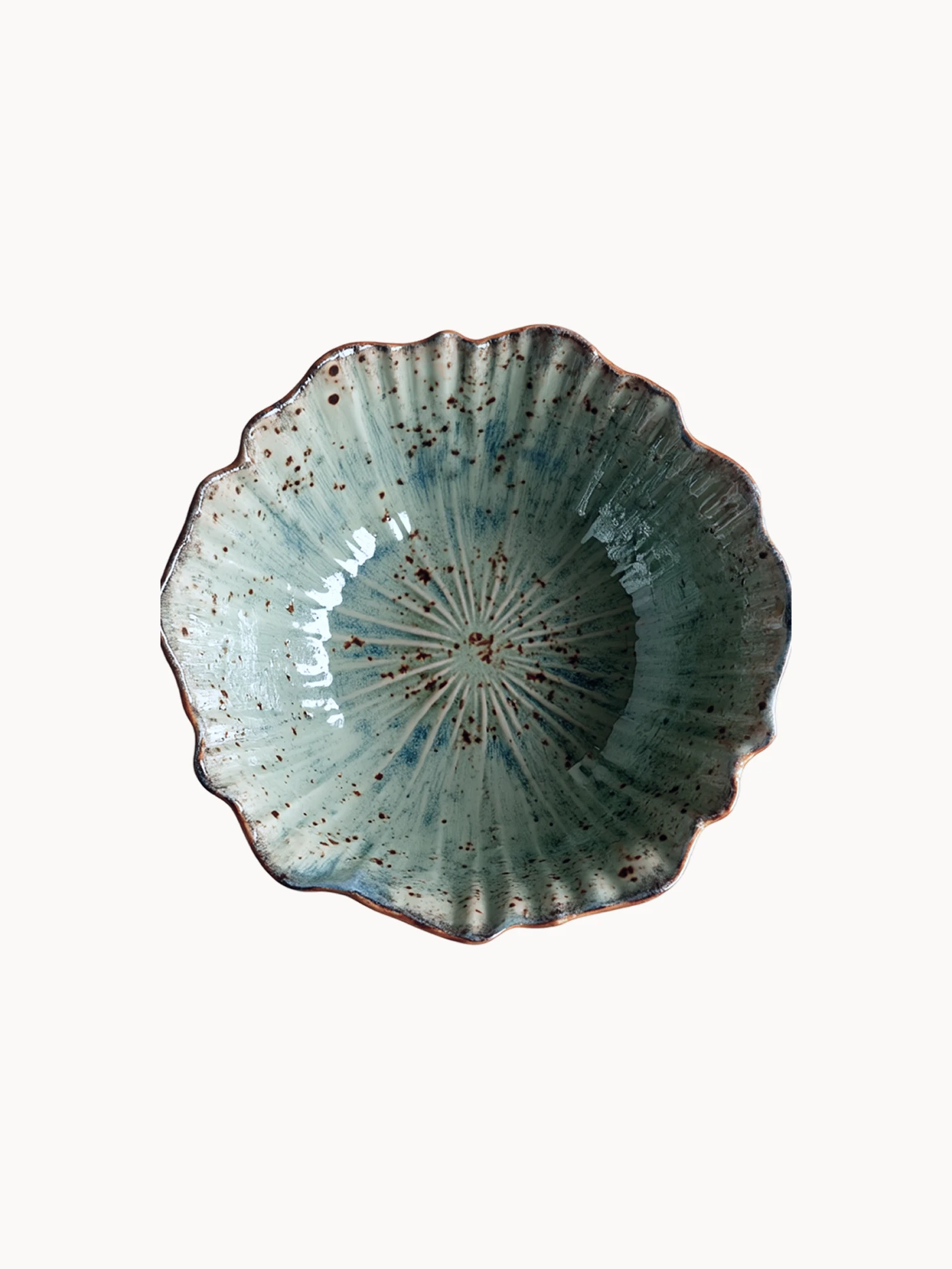 A top-down view on a rustic ceramic bowl with a mottled light blue and beige glaze with brown speckled details, on a plain white background.