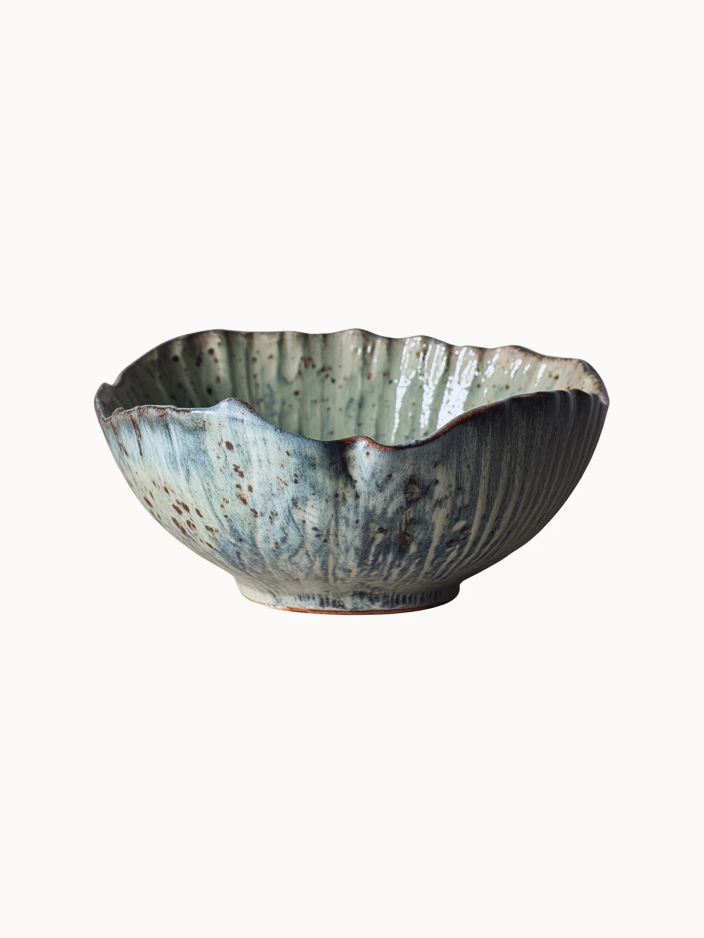 A rustic ceramic bowl with a mottled light blue and beige glaze with brown speckled details, on a plain white background.