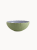 A two-toned ceramic bowl with a finely ribbed, mint  exterior and a smooth lavender interior, on a plain background.