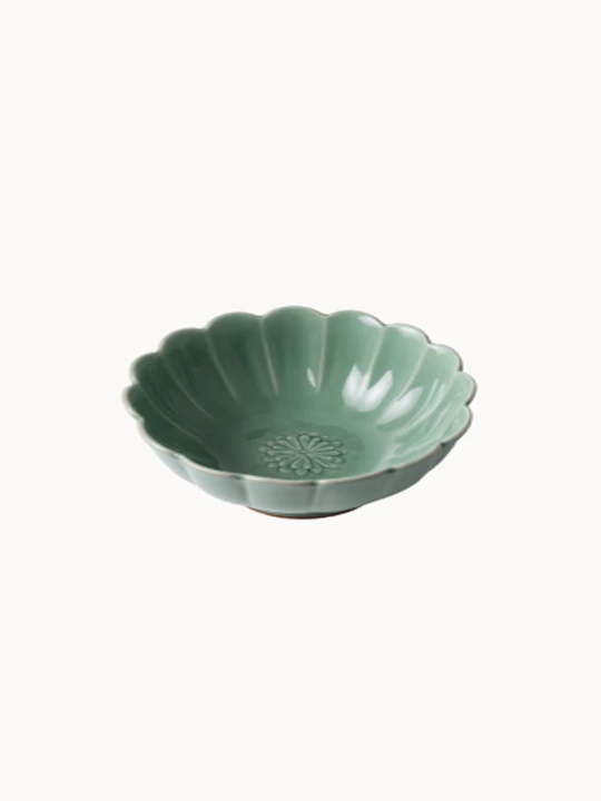 A small, sage green ceramic bowl designed in the shape of a blooming flower,  finished with a smooth glossy glaze, isolated on a plain white background.