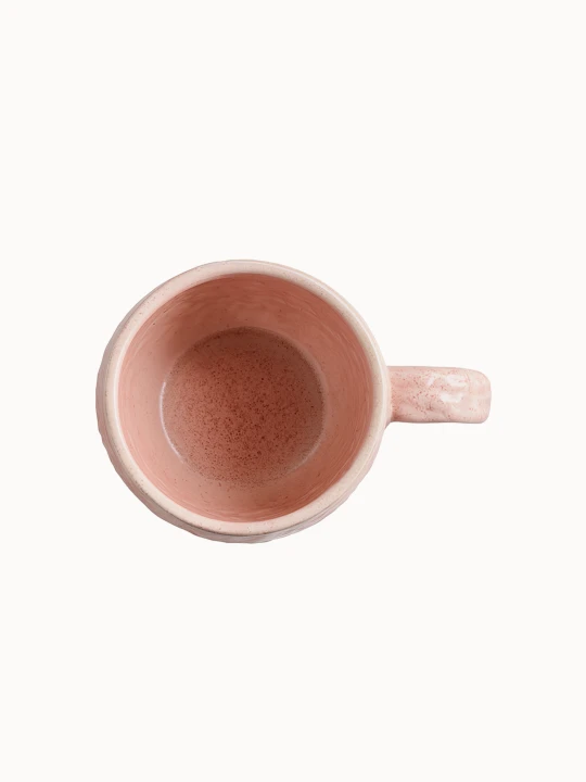 A top-down view on A pink ceramic mug with a bulbous shape and a rounded handle on a plain white background.