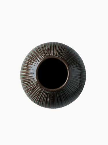 A top-down view on an oval, dark brown ceramic vase with a textured surface covered in vertical ribbed lines and subtle green speckled details, on a white background.